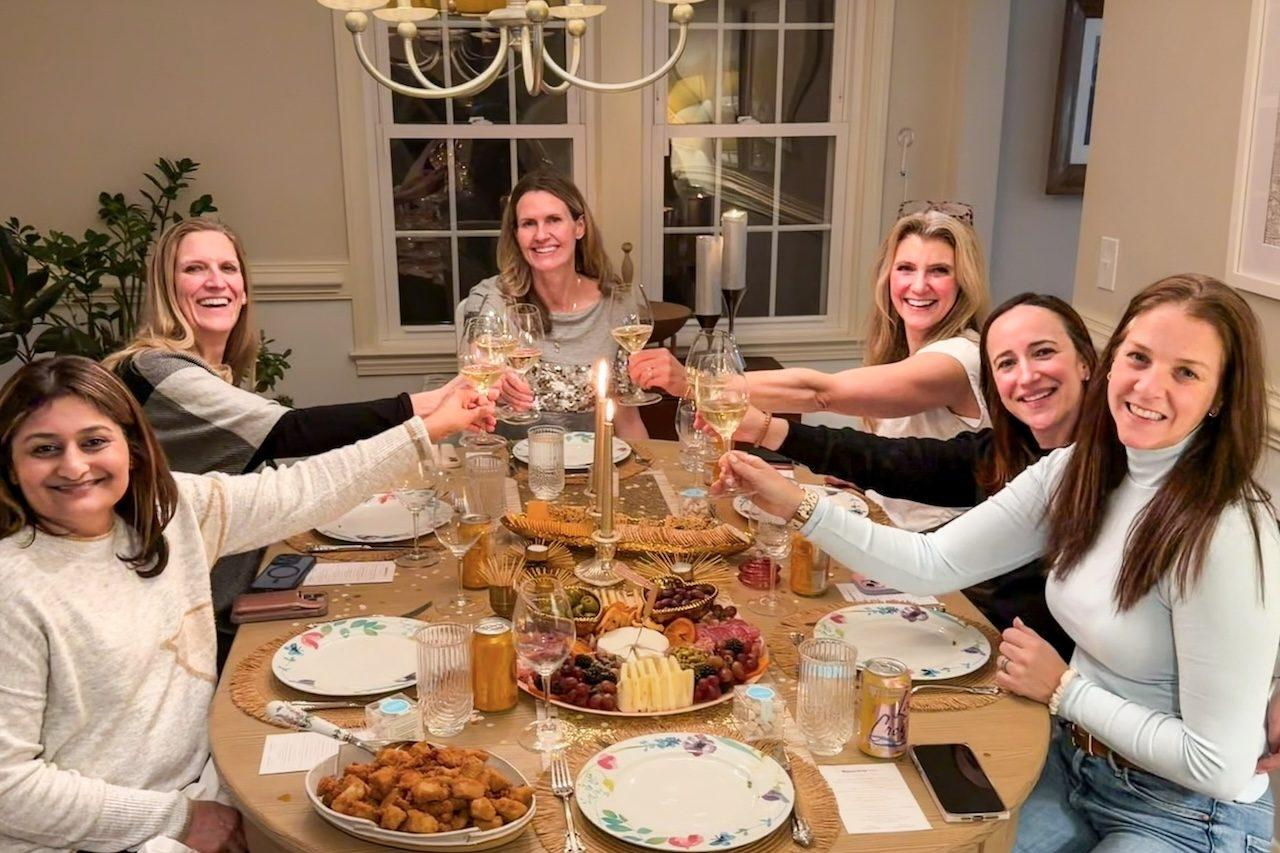 Six friends raising glasses of Champagne around a dinner table at home
