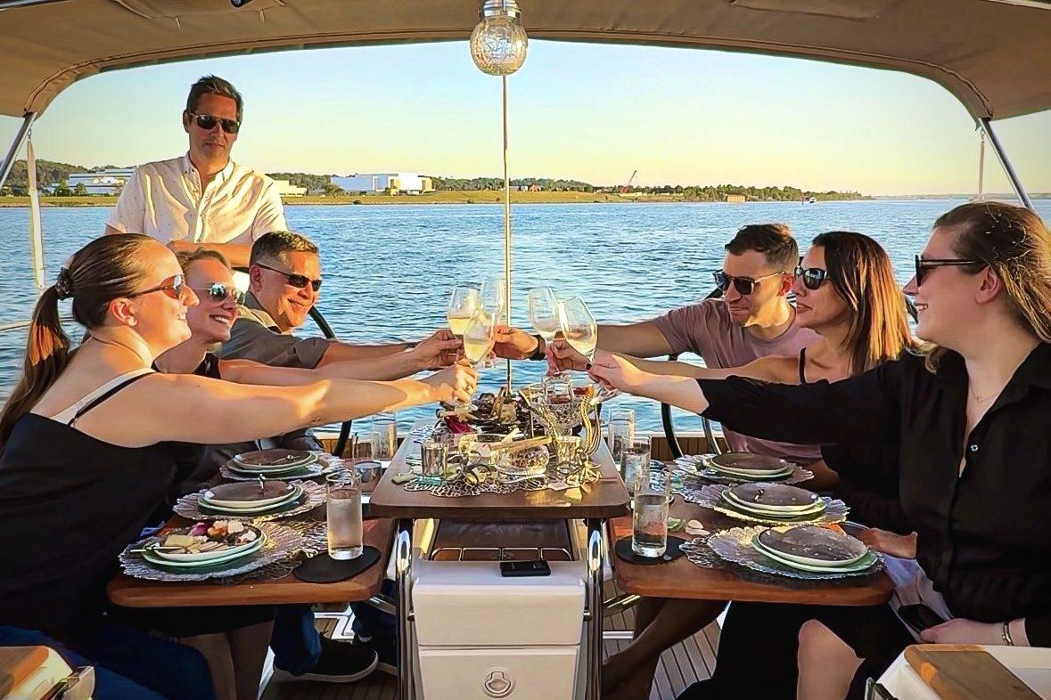 Guests toasting with Champagne around the table of a sailboat at sunset